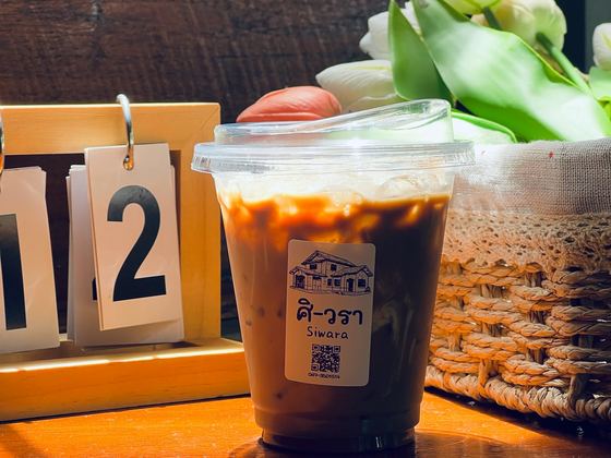 กาแฟเย็นบนโต๊ะไม้ ศิวรา คาเฟ่ / An iced coffee on a wooden table at Siwara Cafe