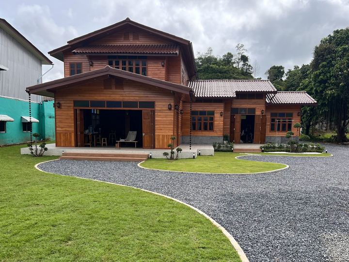 บ้านหลังซ่อมเสร็จ ผนังไม้สีส้มอ่อน สนามหญ้าและทางกรวด / The house after repair, with lawn and gravel drive
